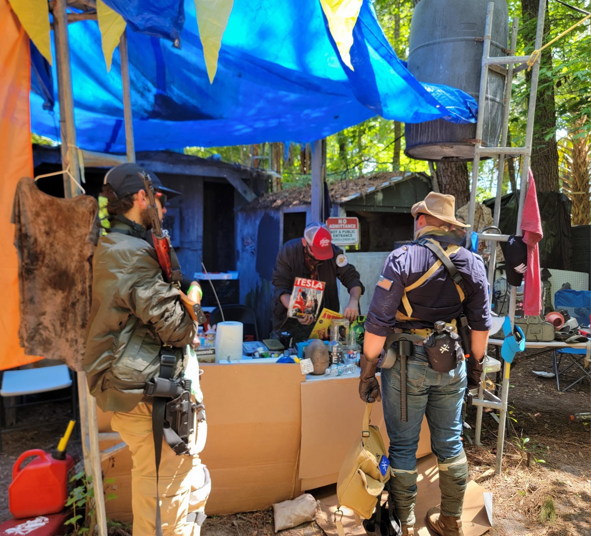 Sunshine Band members running their trading post under blue tarps at a MindGame Productions event