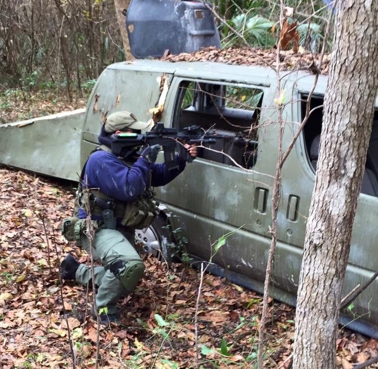 Player taking cover behind an abandoned van in the forest at Amerika