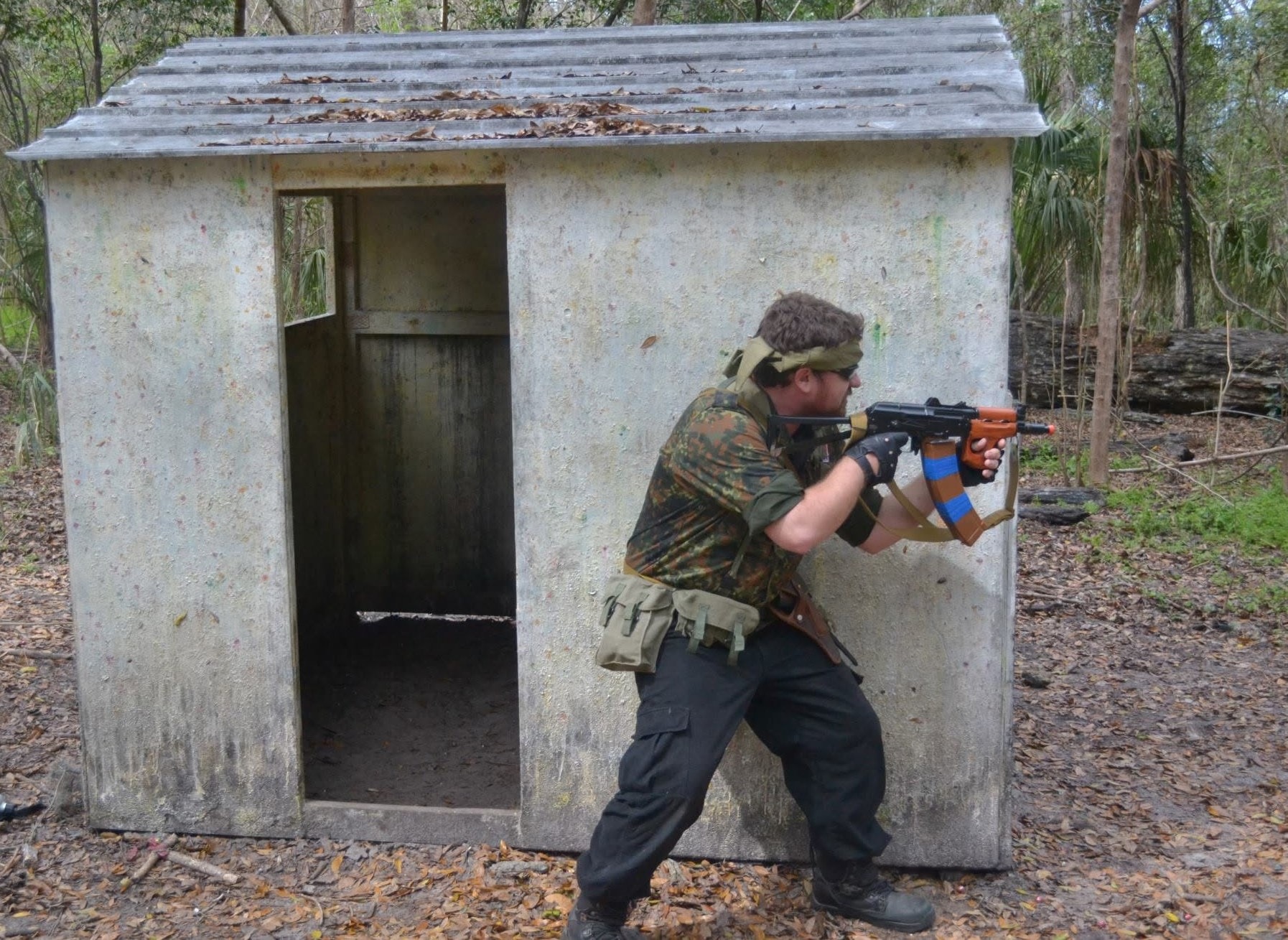 Player in German camo assaulting a concrete bunker with AK at Amerika