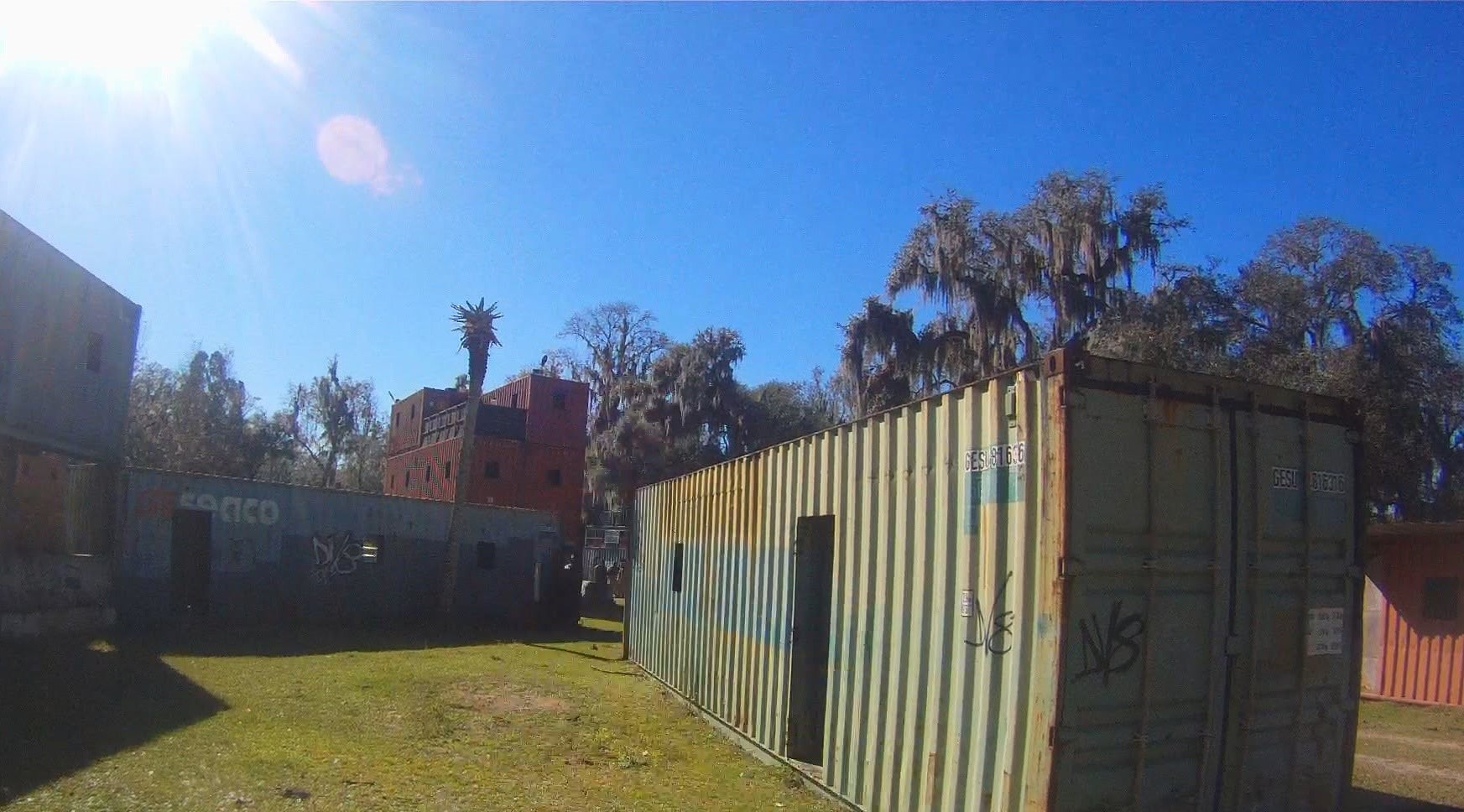 Wide view of the Amerika field with shipping container structures and Spanish moss trees