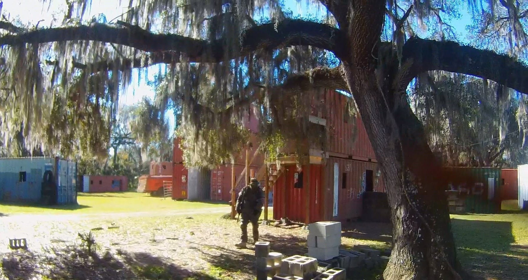 Player advancing through the container village under Spanish moss at Amerika